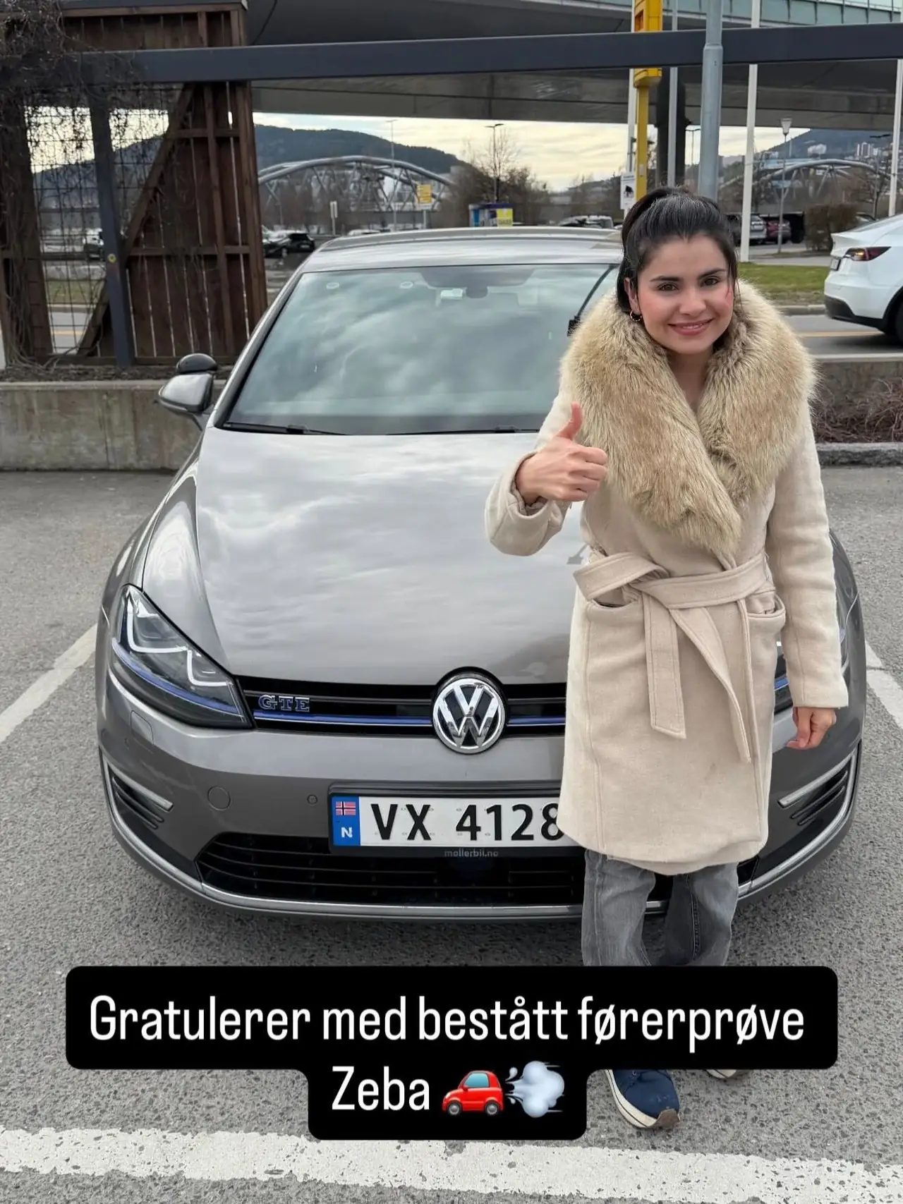 Zeba ved skolens Volkswagen Golf etter bestått førerprøve